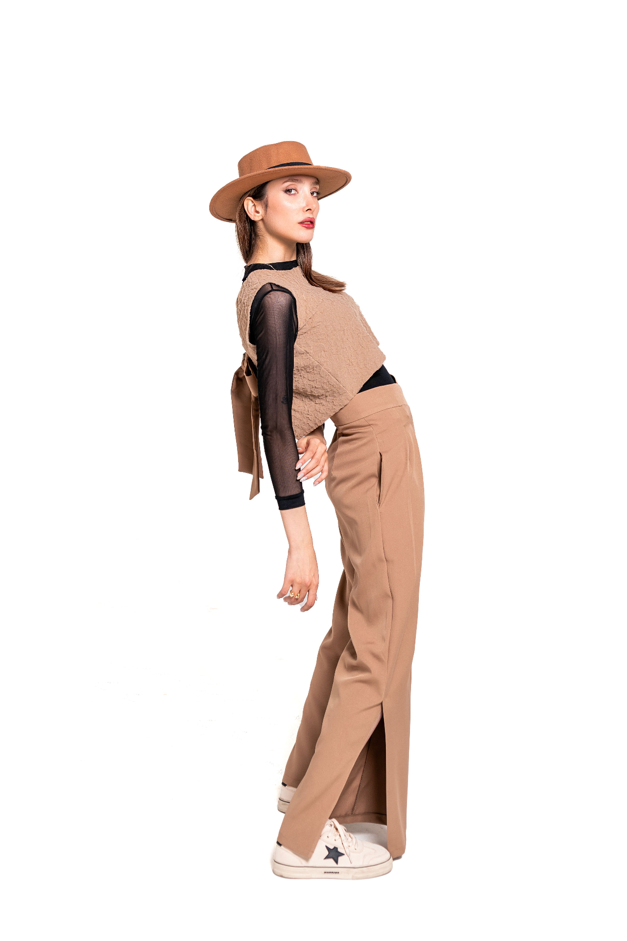 Woman in camel textured crop top and matching high-waist wide-leg trousers with a felt hat