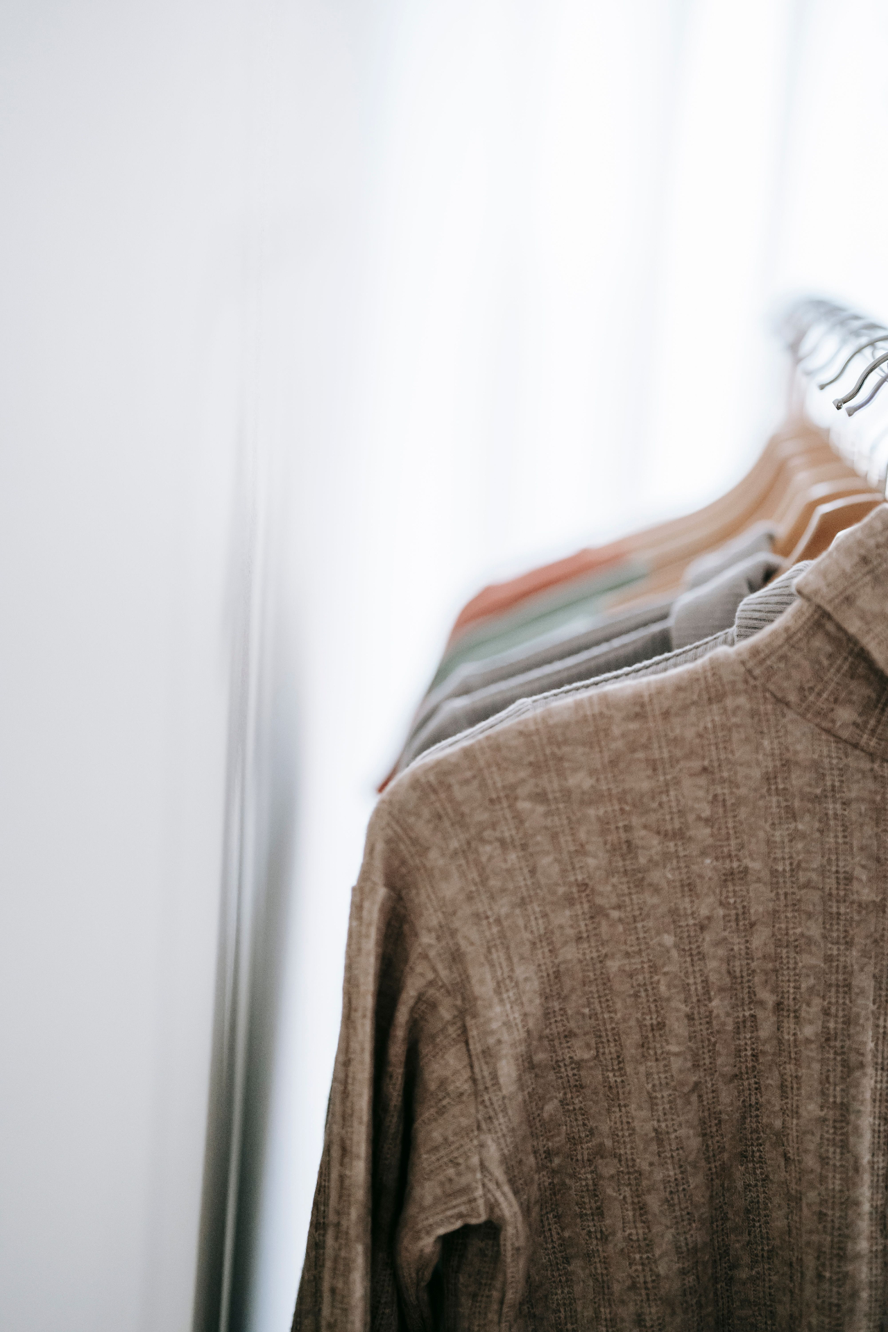 Soft taupe textured shirt hanging by a sunlit window
