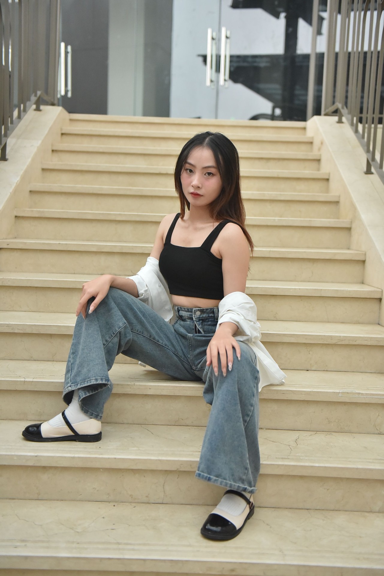 Woman in black crop top and stone-wash relaxed wide-leg jeans on marble steps