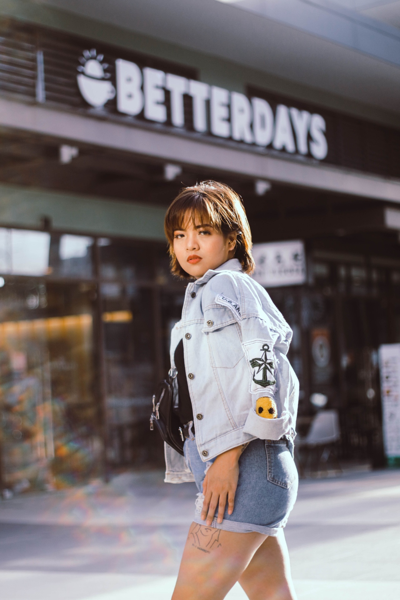 Woman in light-wash denim jacket and matching light-wash denim shorts on a city street