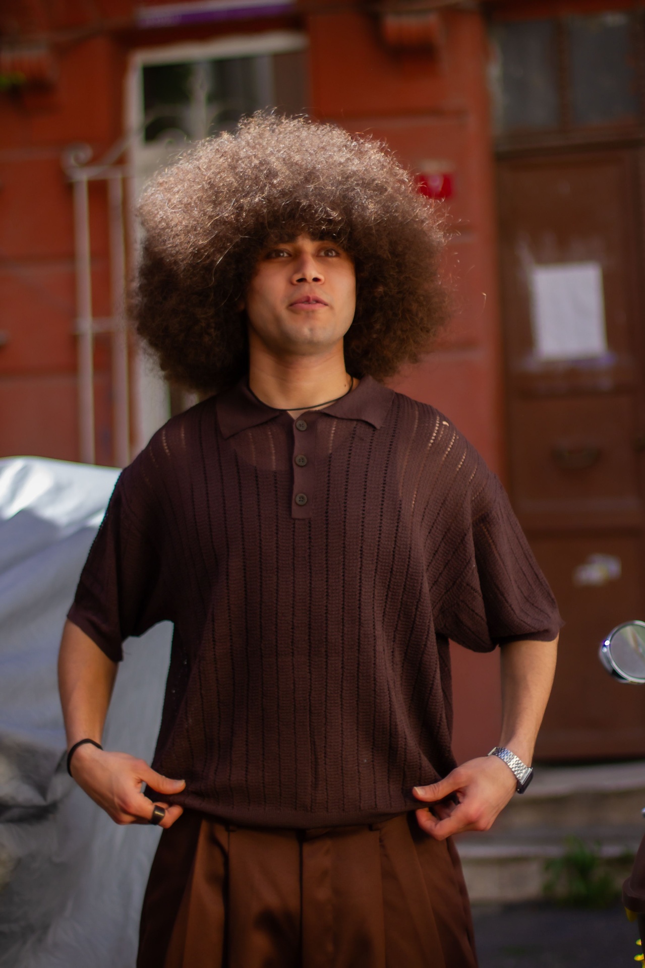 Man in brown ribbed open-knit polo on a city street