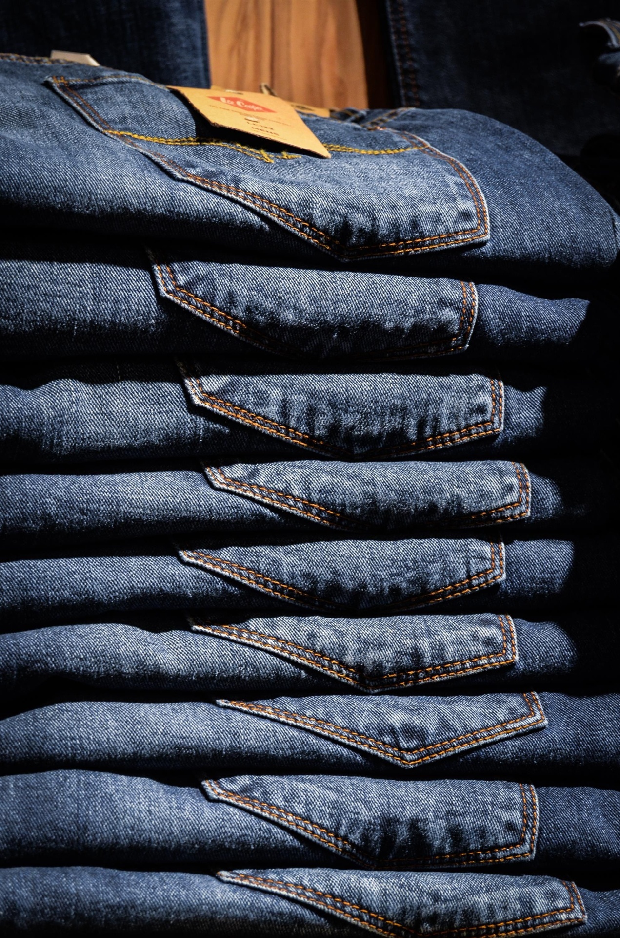 Stack of folded indigo jeans with branded hangtag