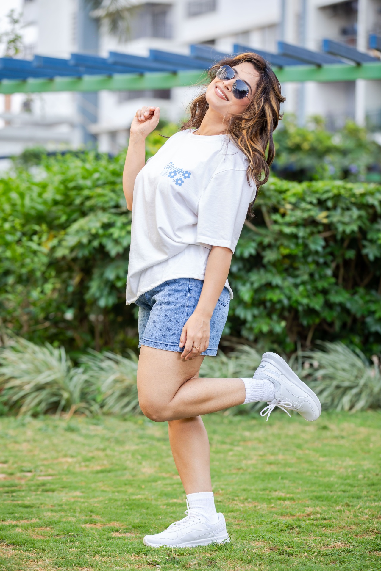 Woman in oversized graphic tee and light-wash star-print denim shorts on a sunny lawn