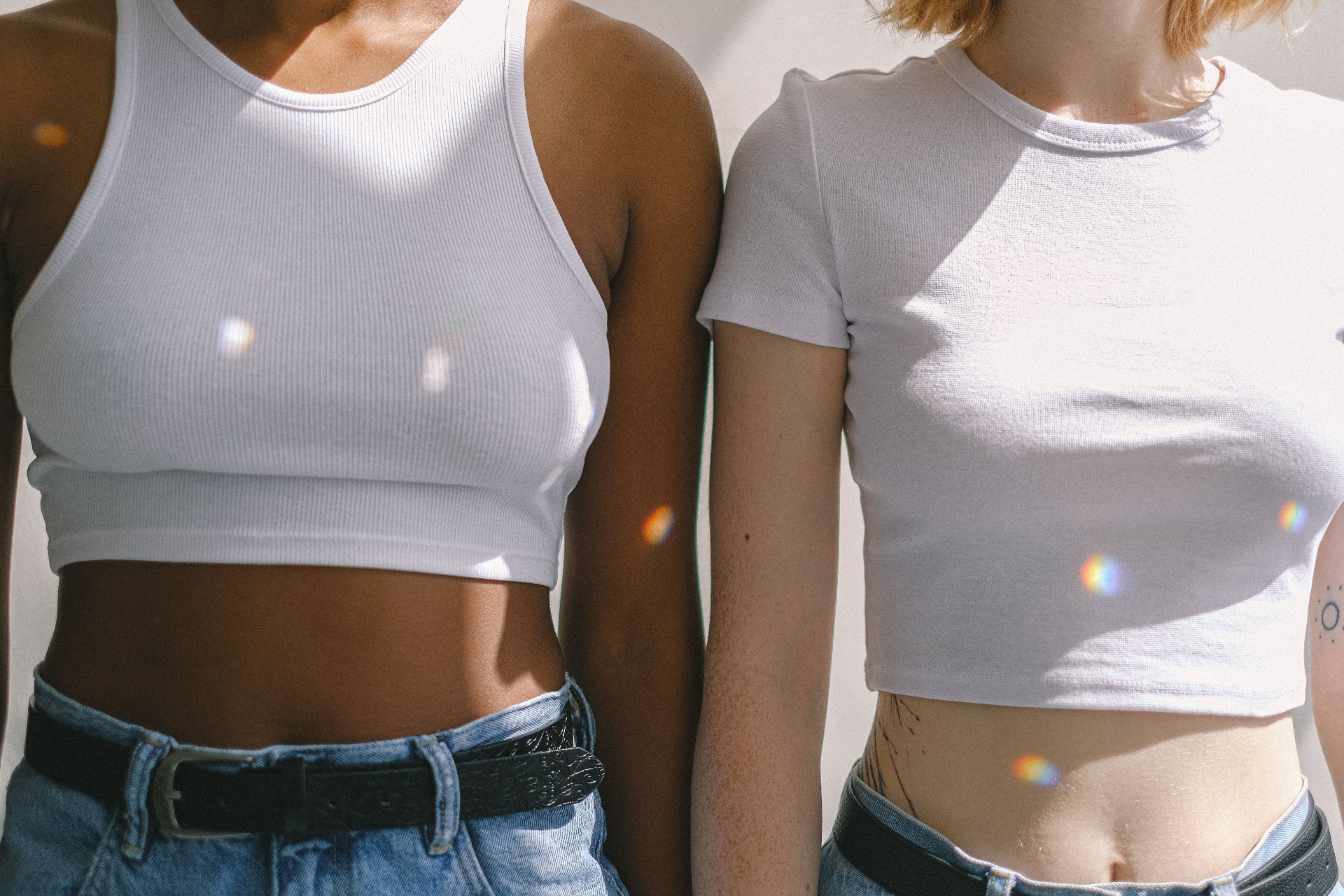 Two women in white ribbed crop tops and denim