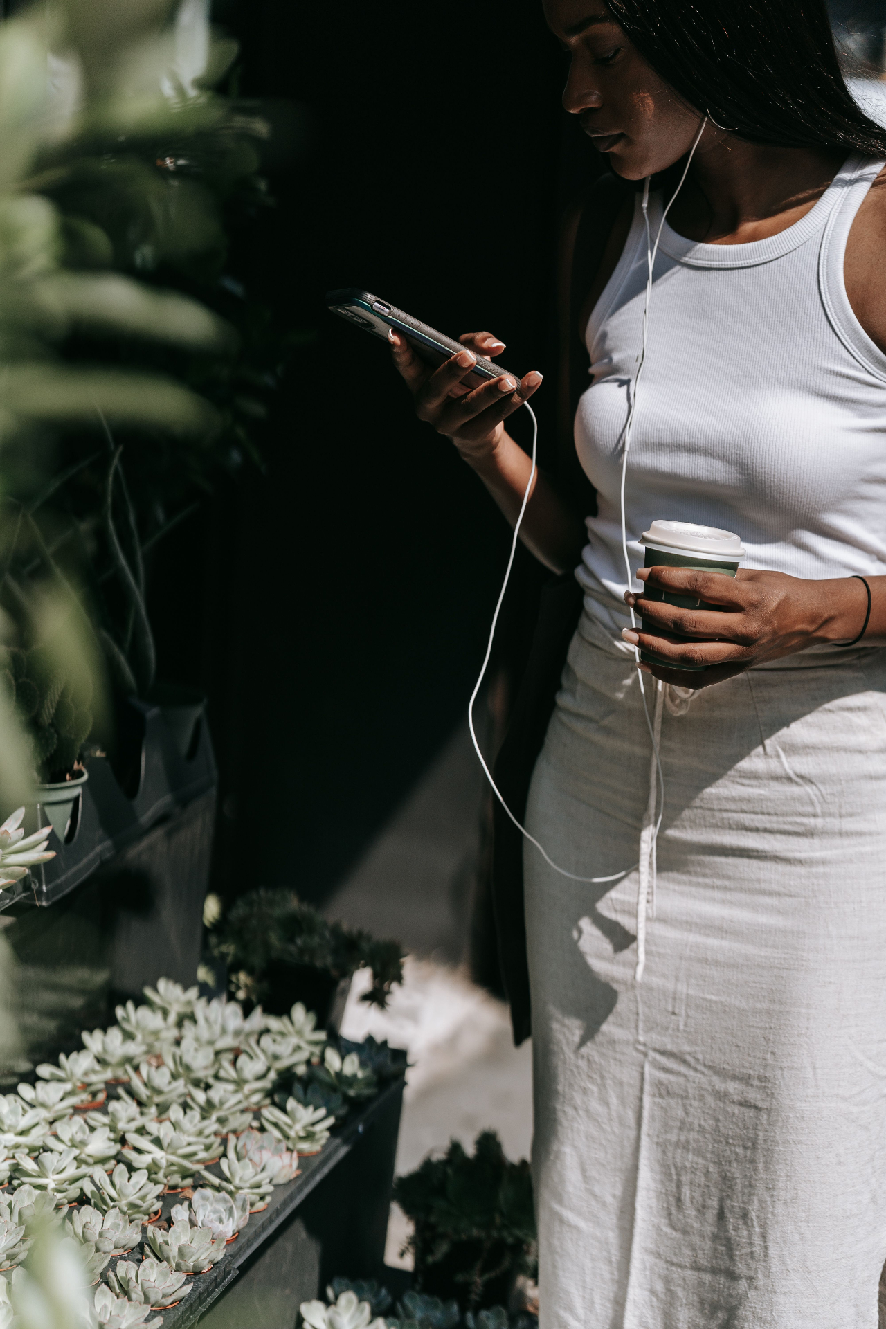 Woman in white ribbed tank and linen skirt with coffee