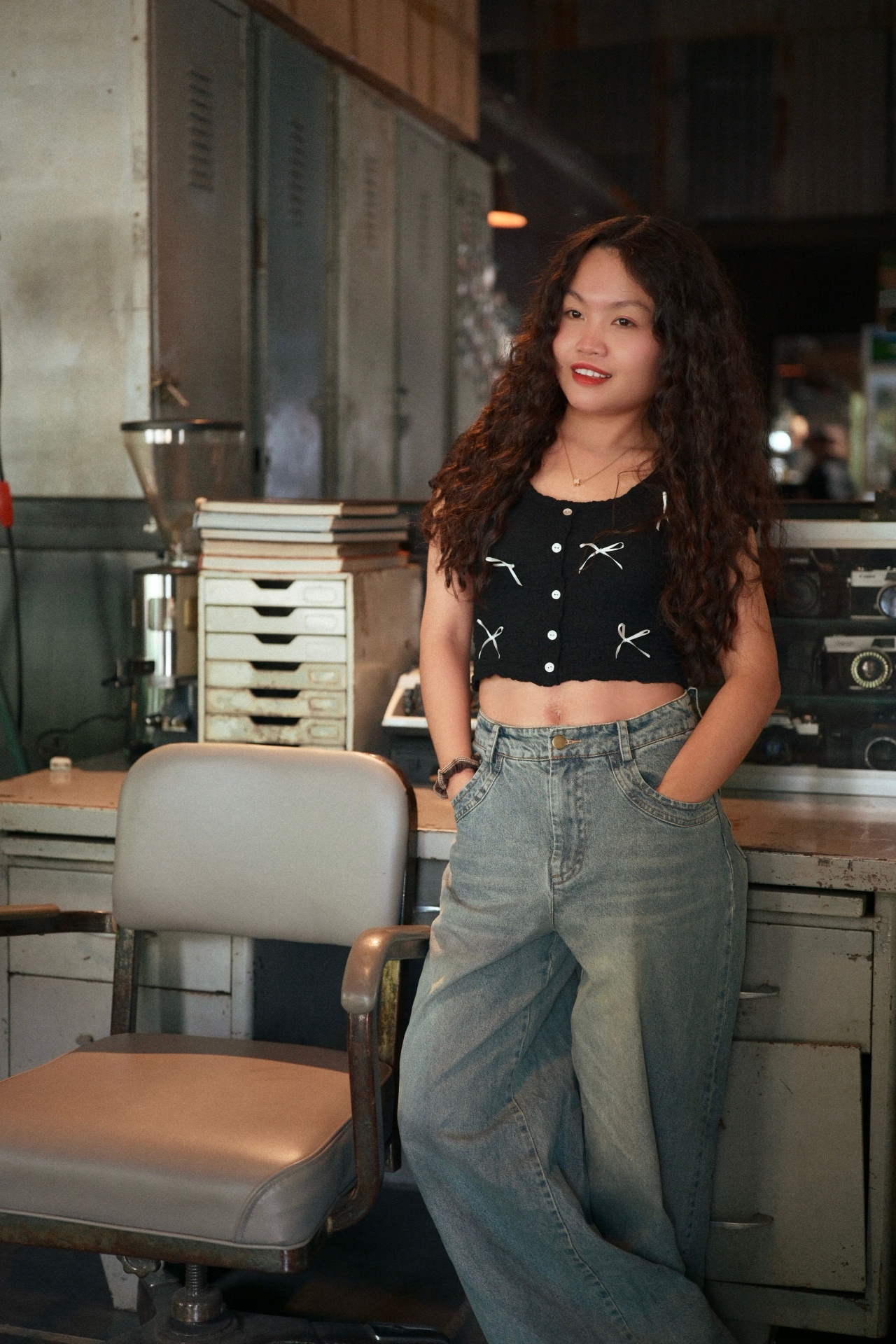 Woman in black bow-print top and light-wash wide-leg baggy jeans in a vintage workshop