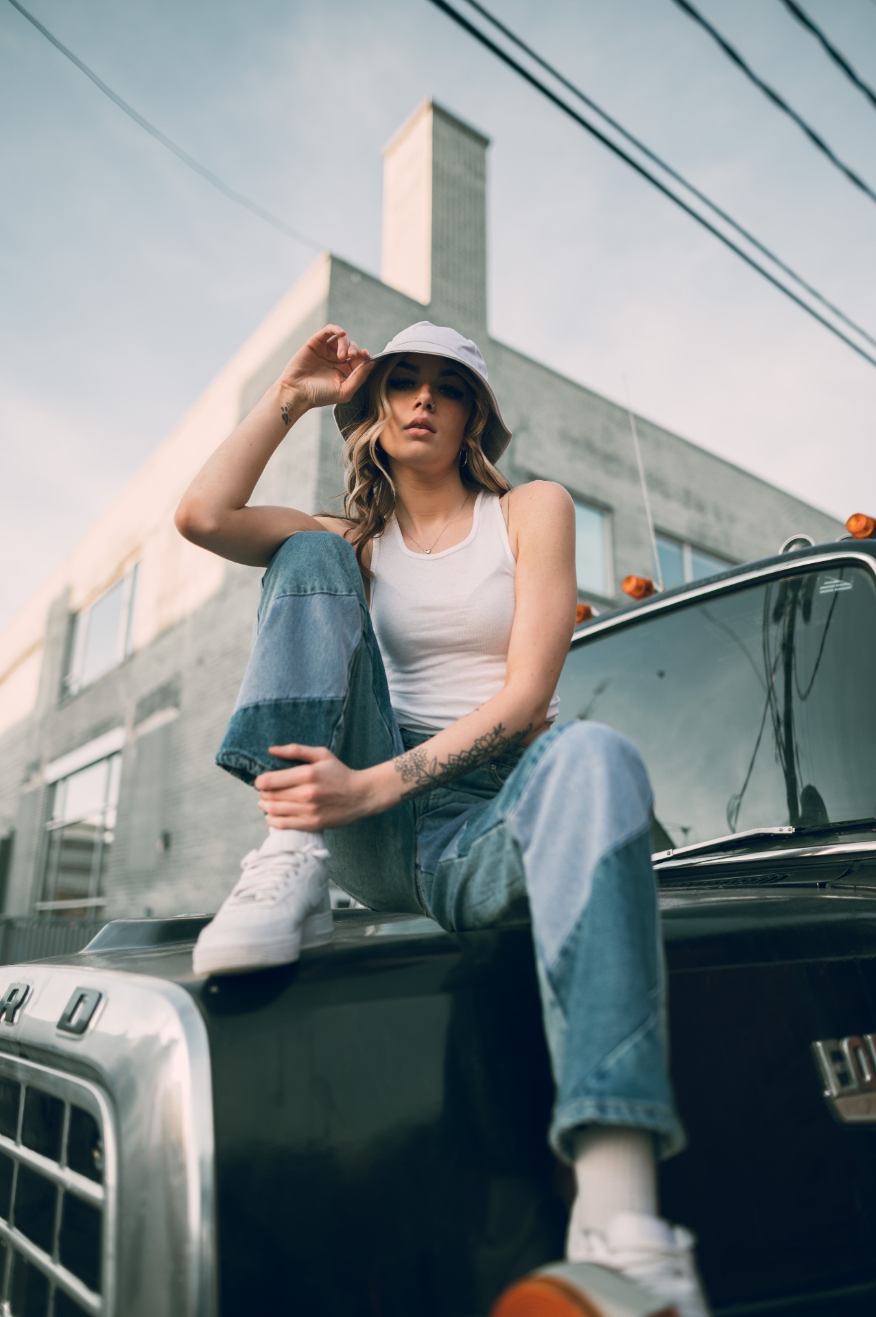 Woman in ribbed white tank and patchwork denim on a vintage truck