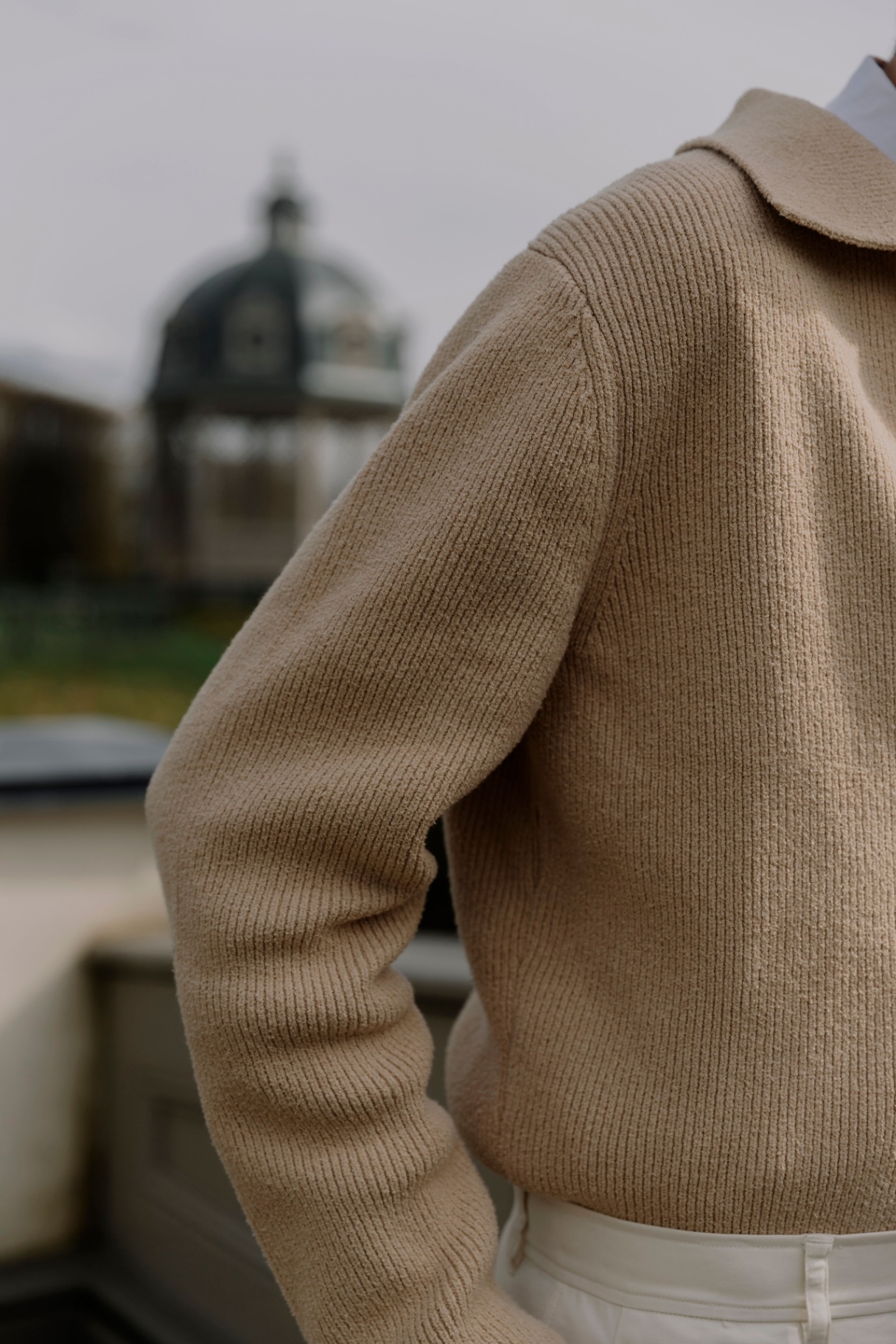 Detail of beige ribbed knit collared sweater outdoors
