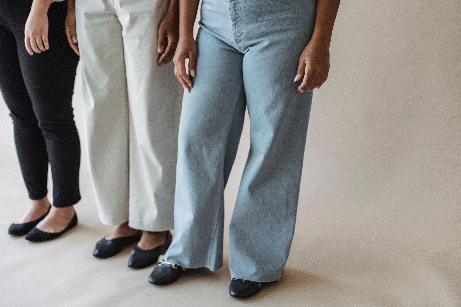 Three women in bottoms, black skinnies, ecru wide-leg chinos and pale blue flared jeans