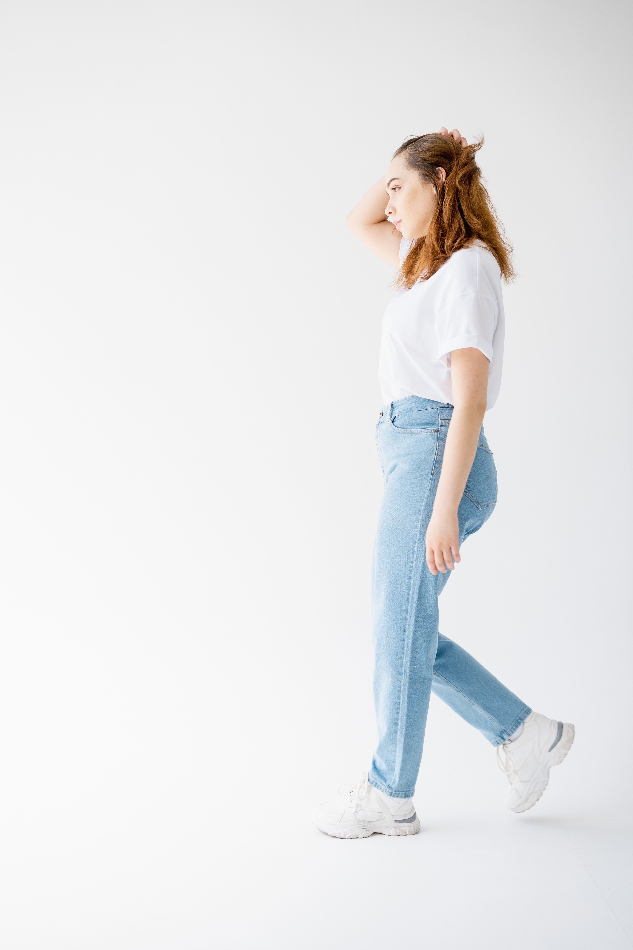 Woman in white crew tee and light-wash straight jeans walking in a studio