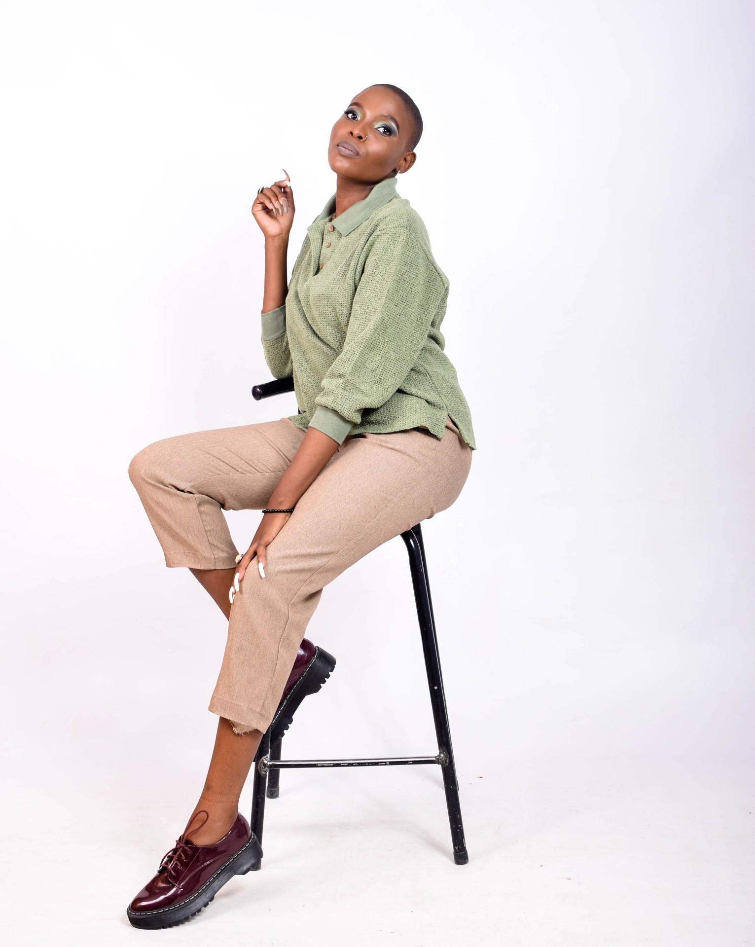 Woman in a sage green waffle-knit polo shirt seated on a stool