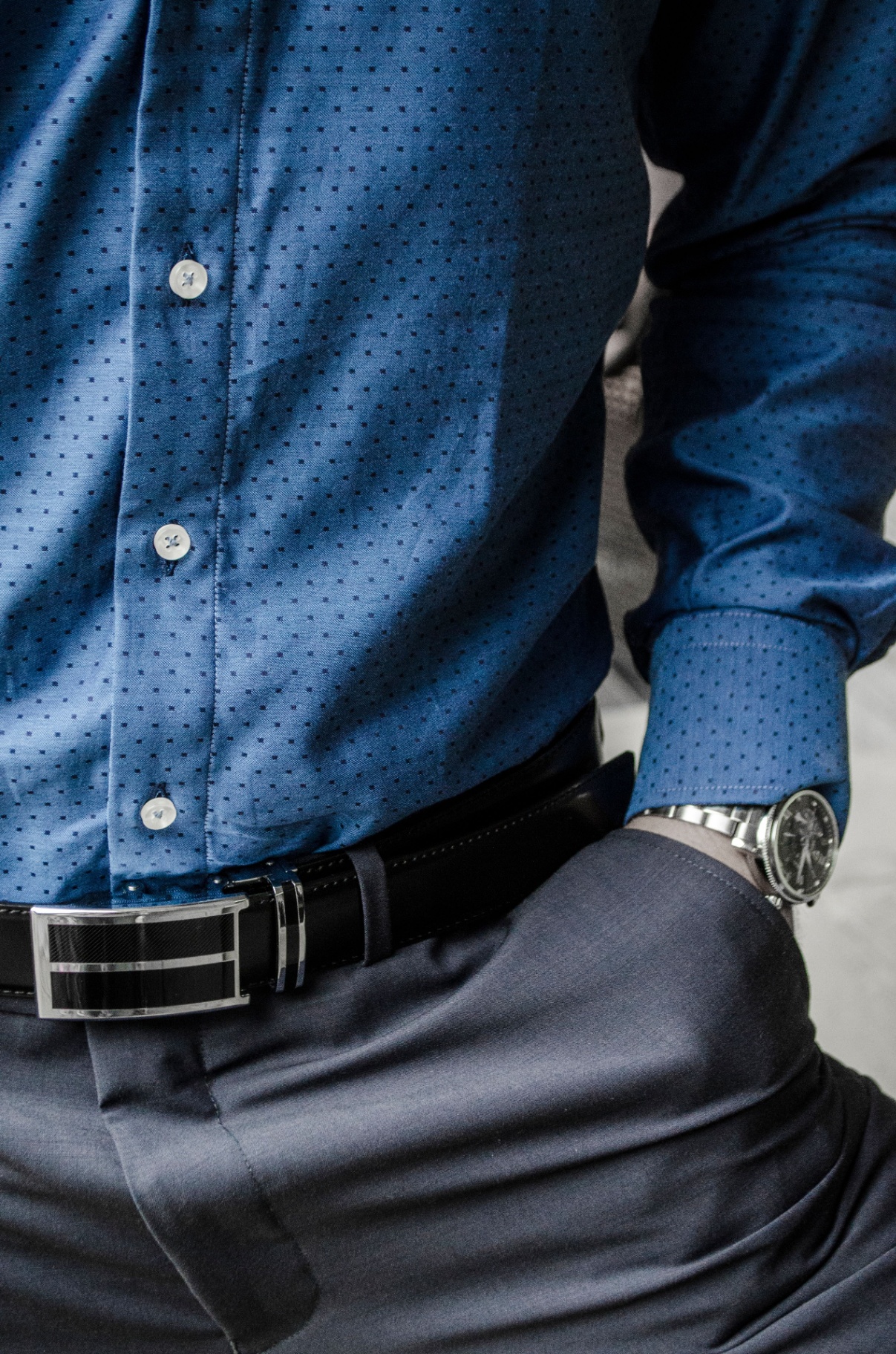 Close-up of a blue micro-dot print button-down shirt with navy trousers and belt