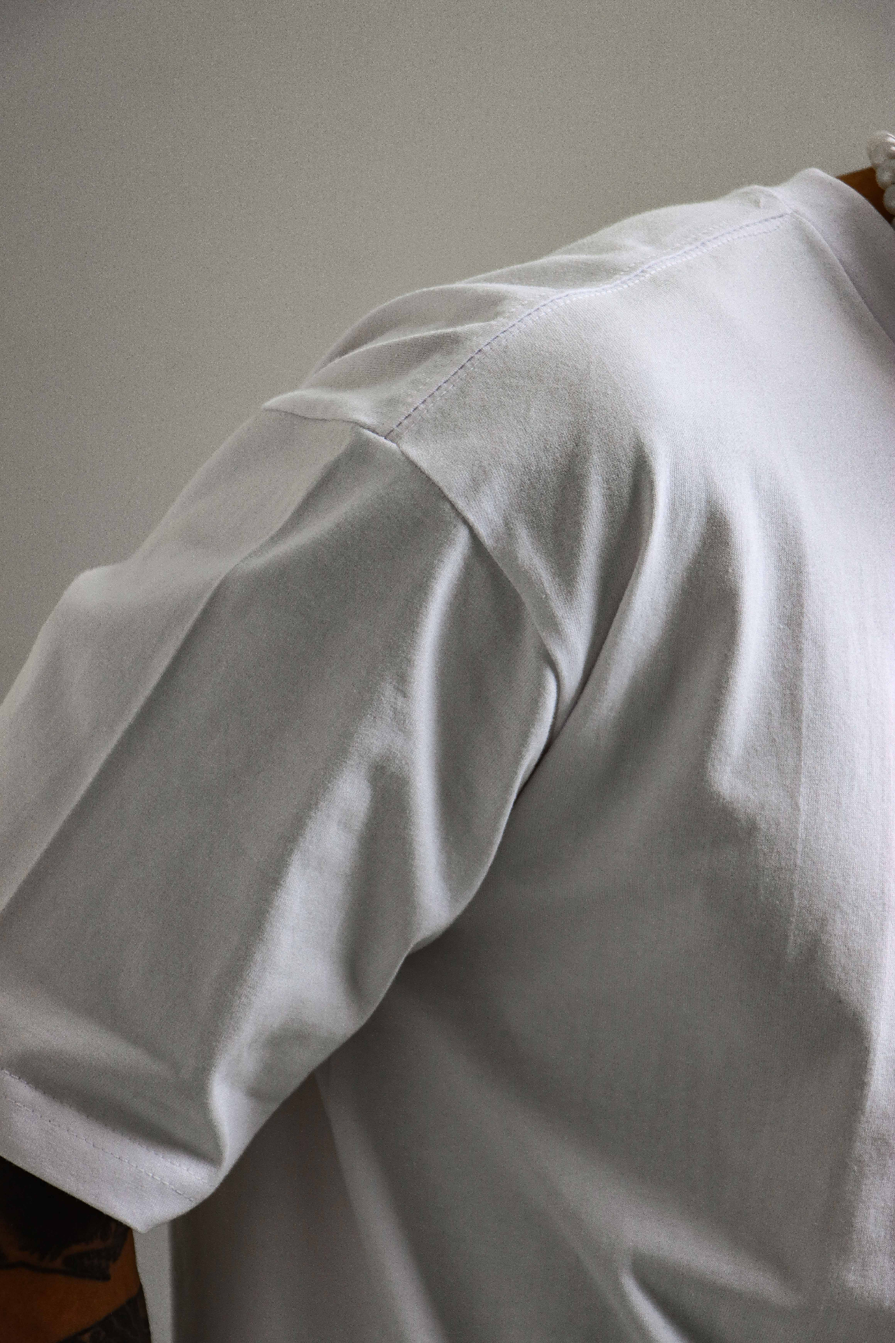 Close-up of a soft grey cotton tee shoulder seam