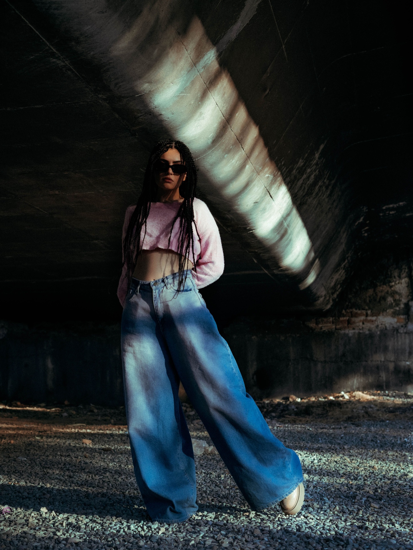 Woman in pink cropped knit and ombre-wash wide-leg jeans under a concrete underpass
