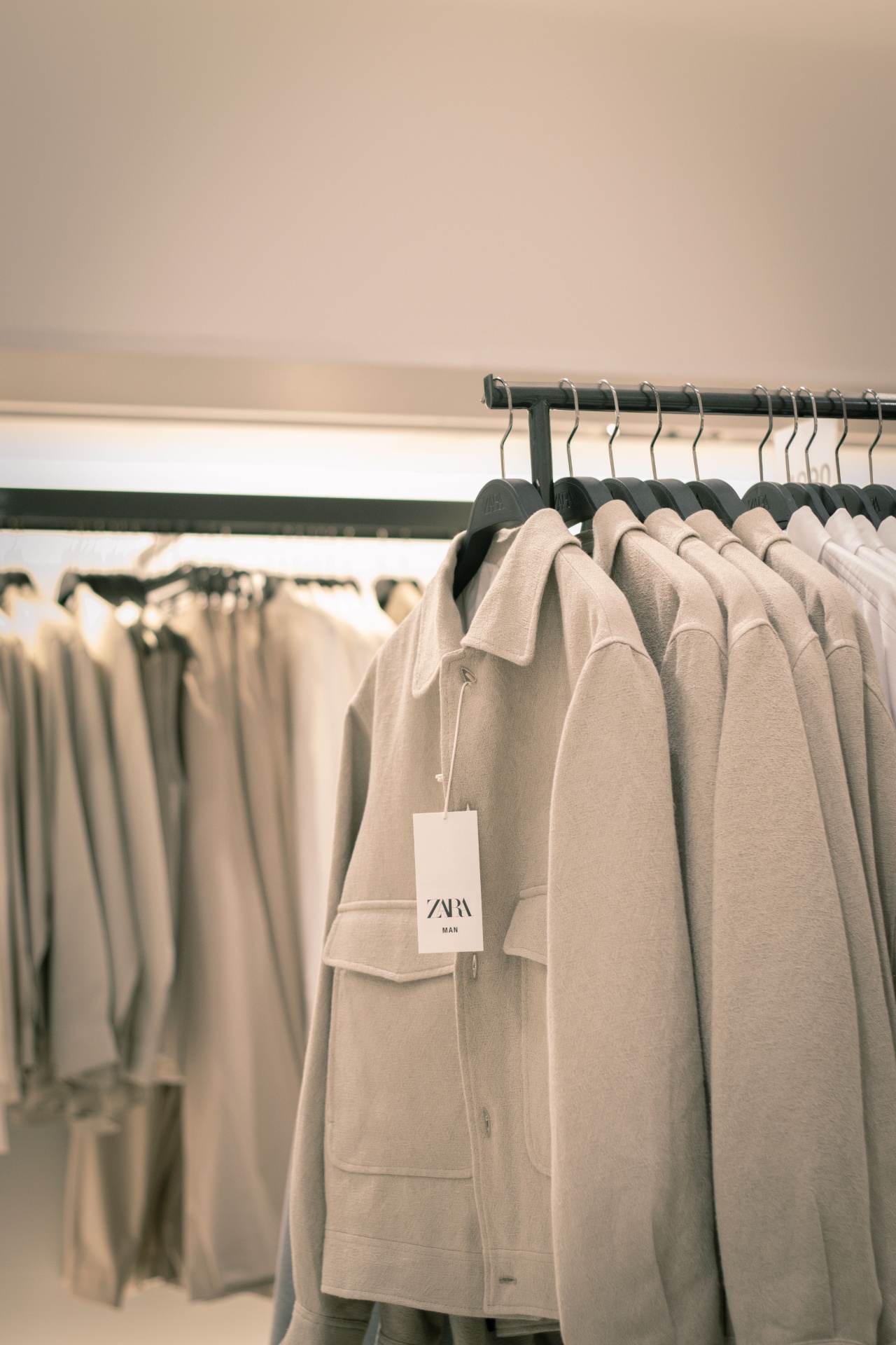 Rack of neutral wool overshirts in a minimalist boutique