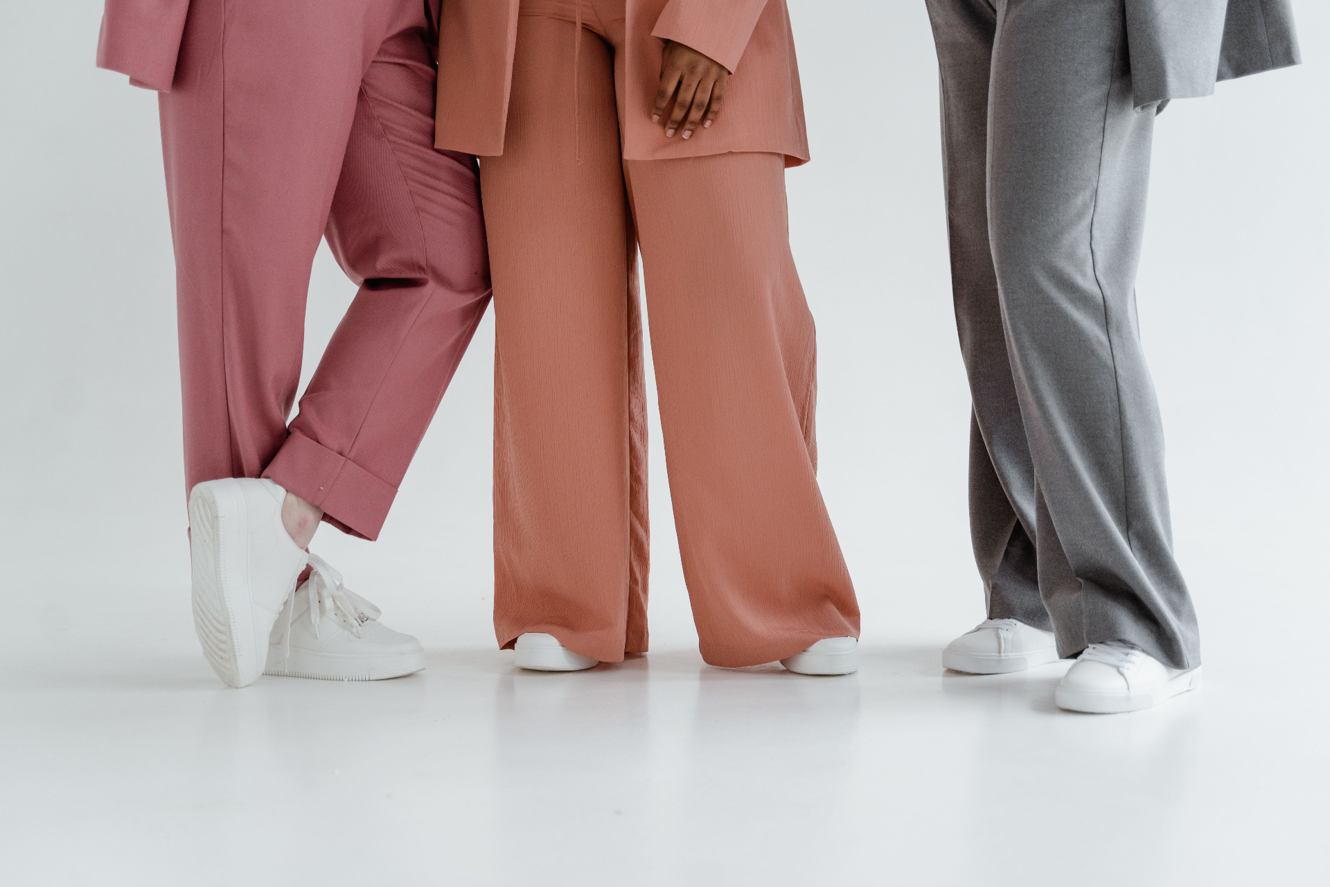 Three tailored suit trouser looks in pink, terracotta and grey from the waist down
