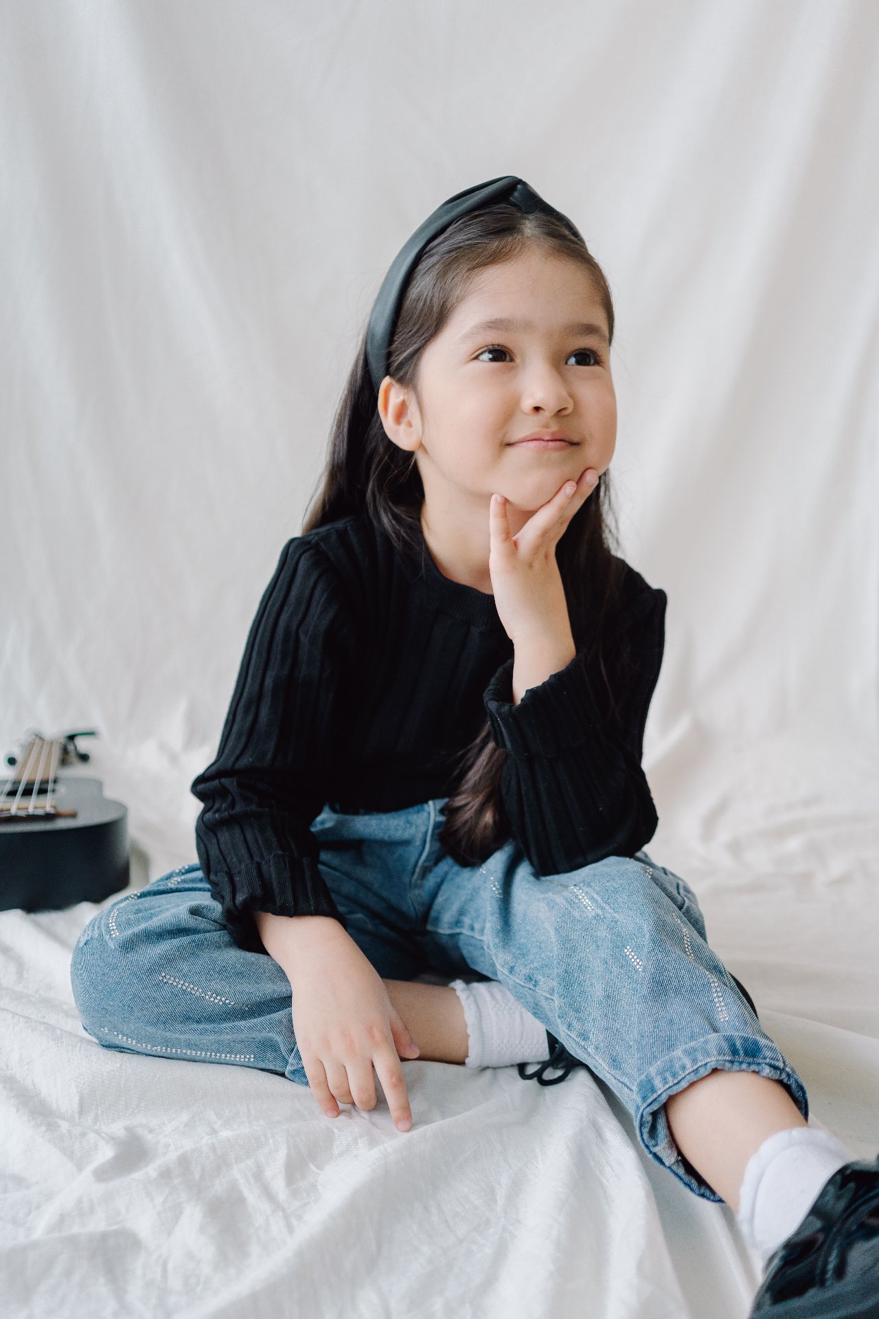 Young girl in black ribbed knit top and light-wash embellished denim jeans