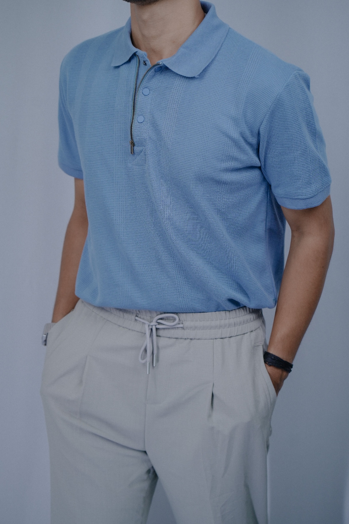 Man in light blue waffle-knit zip polo with linen trousers