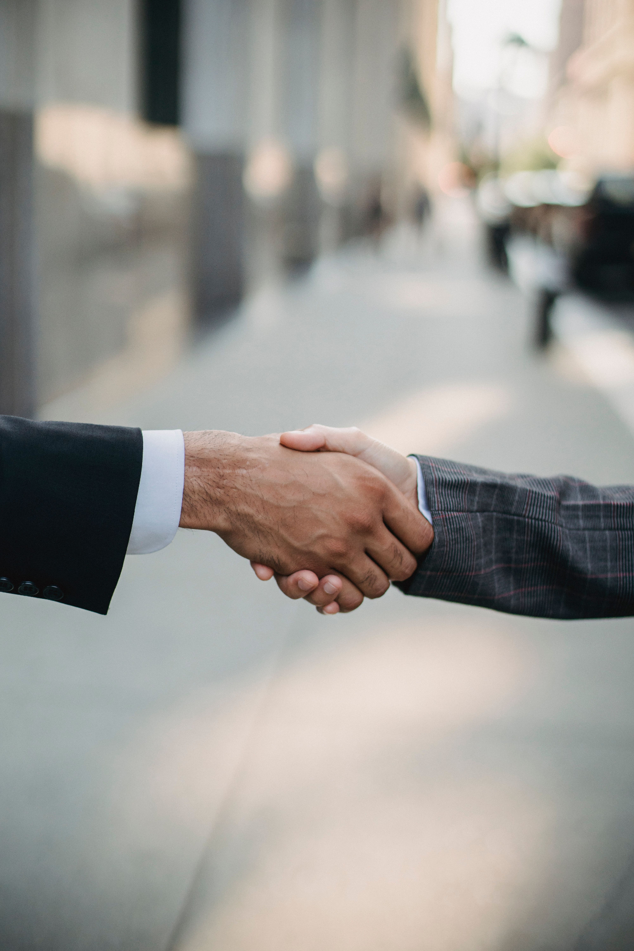 Two businesspeople shaking hands on a city street