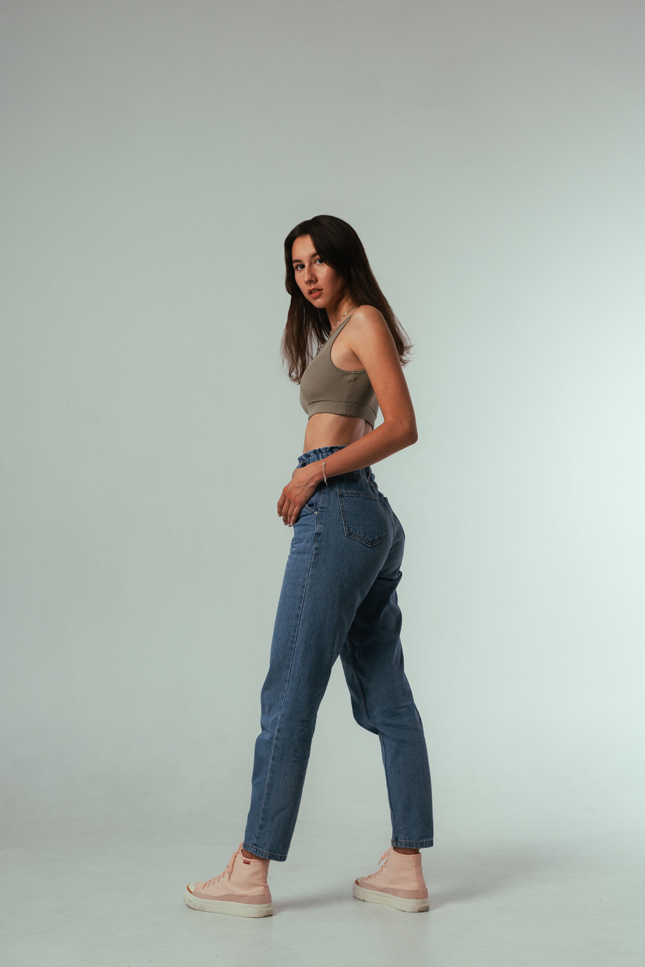 Woman in taupe rib crop bralette and paperbag mom jeans in a studio